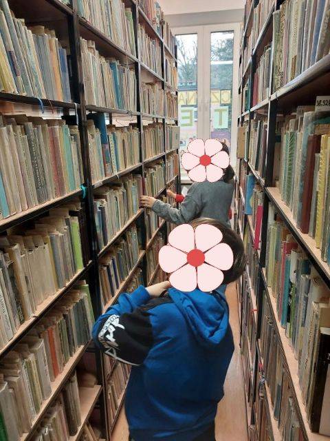 Biblioteczny escape room. Dzieci szukają książek na półkach w magazynie.