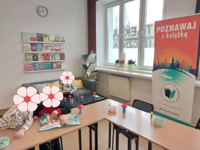 Czytelnictwo dzieci. Dzieci siedzą przy stolikach i oglądają książki.